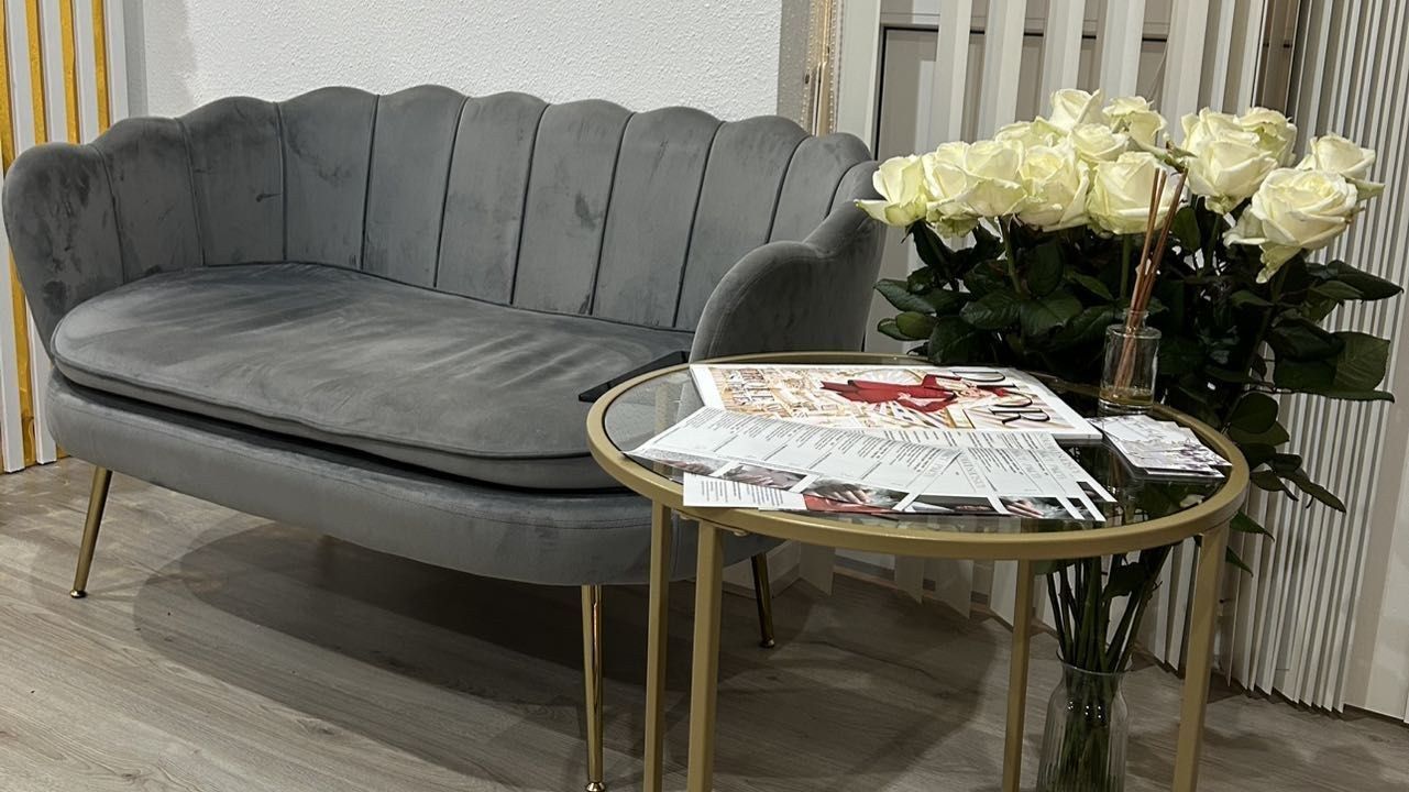 De wachthoek in de salon: een grijze fluwelen bank, een gouden bijzettafel en witte rozen
