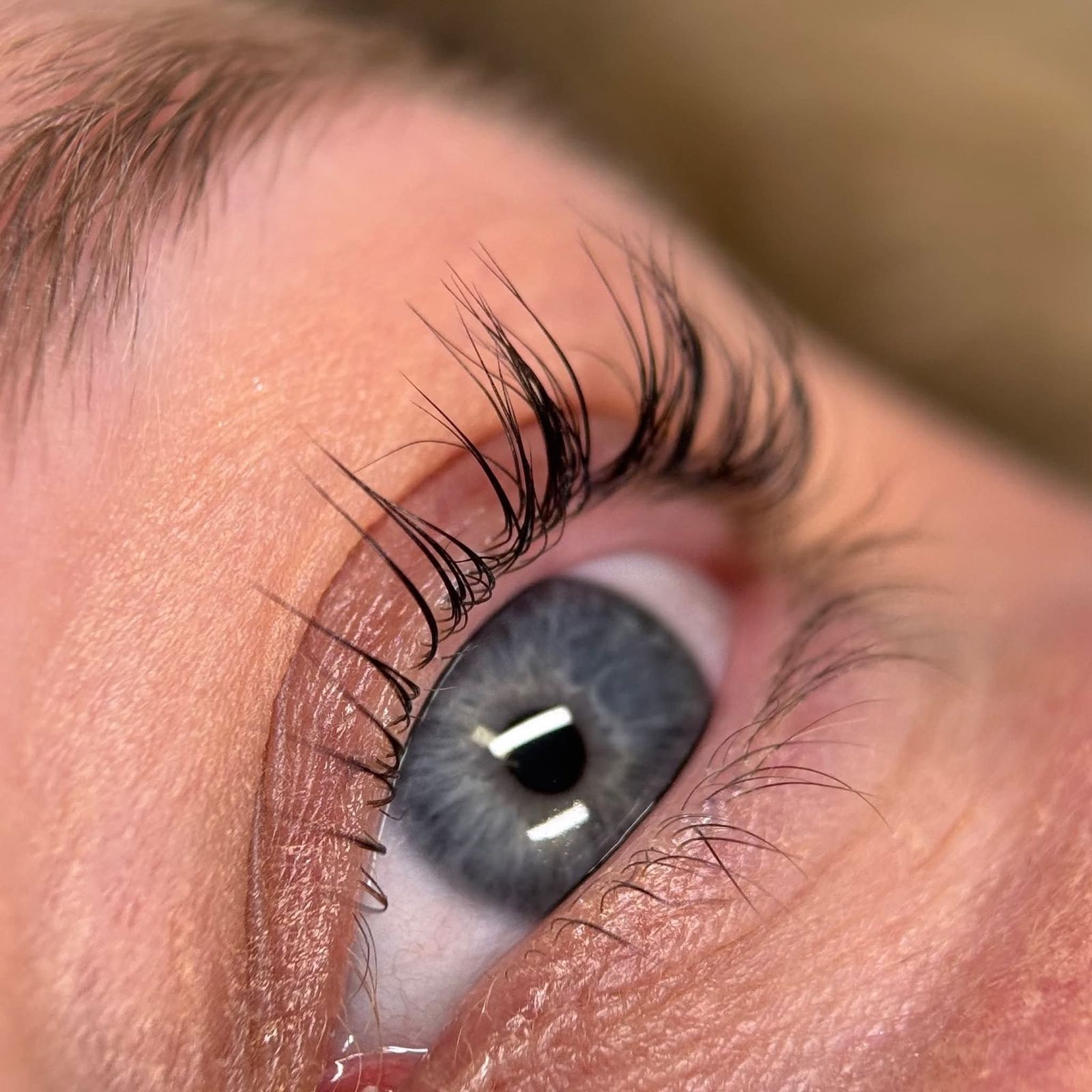 Opgekrulde wimpers boven een grijs oog na een lash lift