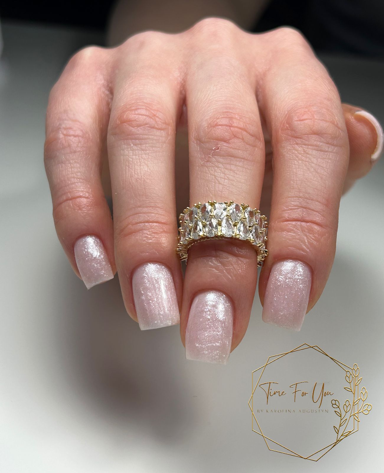 Korte lichtroze parelmoer nagels met een gouden ring