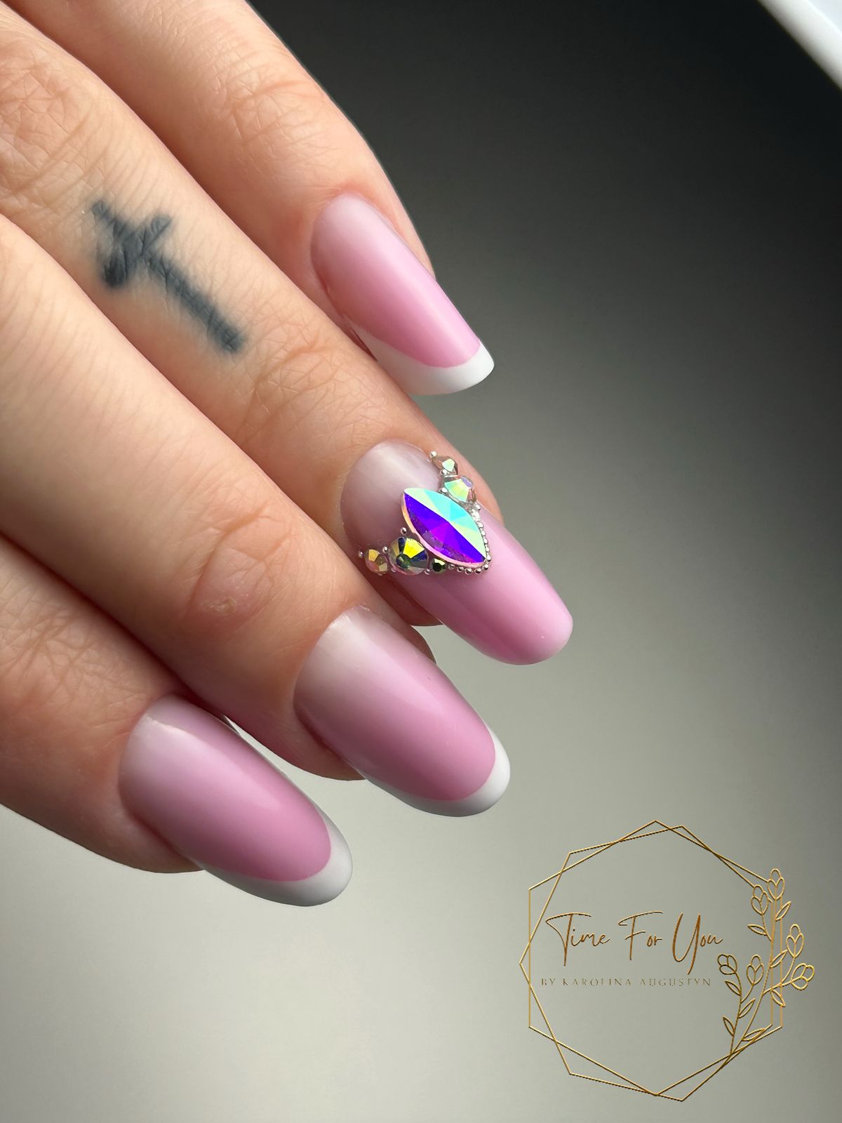 Roze amandelvormige nagels met witte french en een glinsterende steen