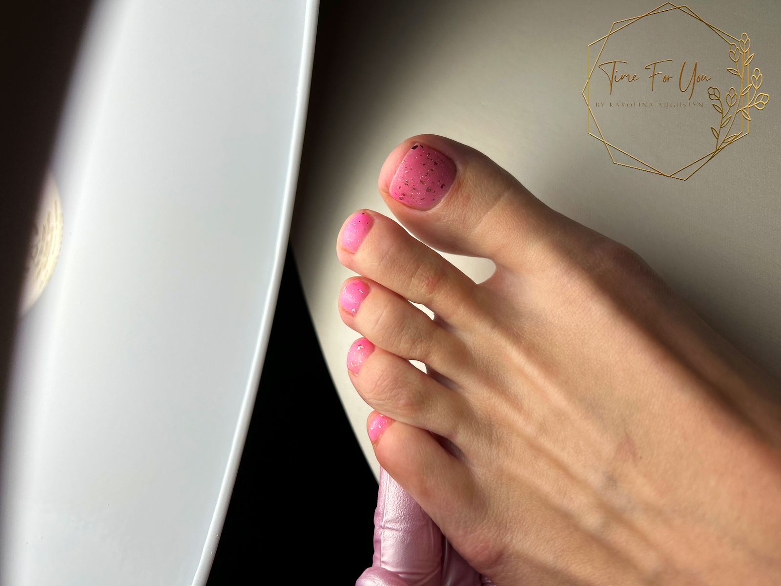 Voeten met roze gelnagels en stipjes tijdens een pedicure
